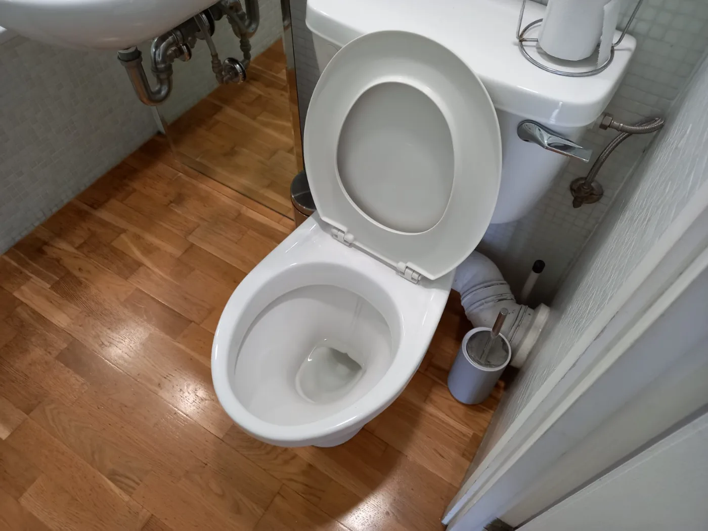 Toilet and wood floor cleaned in a small bathroom